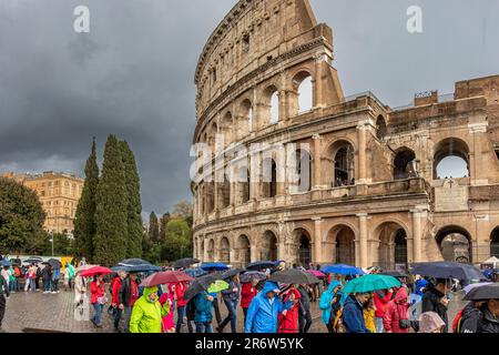 Visiteurs avec des parasols sous une forte pluie et un ciel sombre au-dessus du Colisée, Rome, Italie Banque D'Images