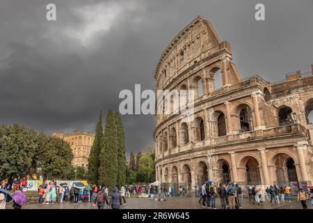 Visiteurs avec des parasols sous une forte pluie et un ciel sombre au-dessus du Colisée, Rome, Italie Banque D'Images