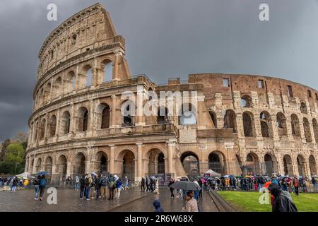 Visiteurs avec des parasols sous une forte pluie et un ciel sombre au-dessus du Colisée, Rome, Italie Banque D'Images