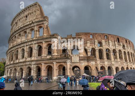 Visiteurs avec des parasols sous une forte pluie et un ciel sombre au-dessus du Colisée, Rome, Italie Banque D'Images