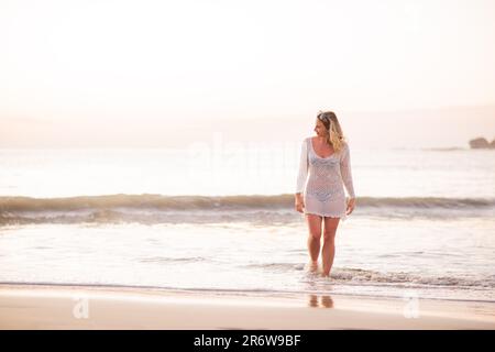 Femme blonde debout sur la plage en crochet blanc maillot de bain couvert au Nicaragua sur l'océan pacifique près de San Juan del sur au coucher du soleil dans l'eau Banque D'Images