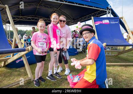 Warrington, Cheshire, Royaume-Uni. Dimanche 11 juin 2023 ; Warrington, Cheshire, Royaume-Uni ; Race for Life in Victoria Park in AID of cancer Research. Des centaines de personnes habillées en rose ont participé à différents événements de collecte de fonds à l'aide de la recherche sur le cancer. Ici, un homme crée des coiffures à partir de ballons. Crédit : John Hopkins/Alamy Live News Banque D'Images