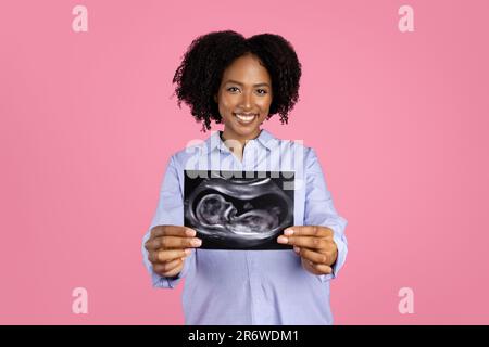 Jeune femme maurille afro-américaine souriante dans une ambiance décontractée avec le ventre grand spectacle d'ultrasons tourné Banque D'Images