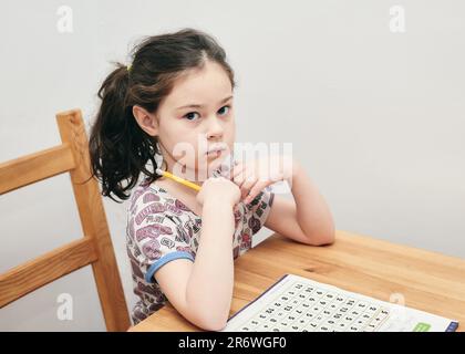 jolie fille résoudre des puzzles mathématiques à la table de cuisine Banque D'Images