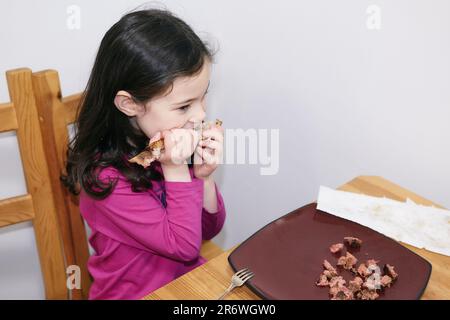 jeune fille aux dents changeantes travaillant sur une côte de porc énorme Banque D'Images