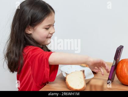 mignon jeune fille avec une dent primaire manquante parle tout en mangeant un repas Banque D'Images