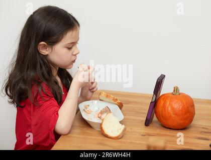 mignon jeune fille avec une dent primaire manquante parle tout en mangeant un repas Banque D'Images