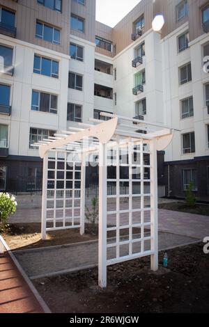 arche en bois blanc dans la cour d'un bâtiment de plusieurs étages. Banque D'Images