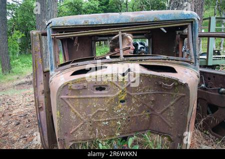 Une femme adulte s'assoit dans une vieille voiture à risque. Région pittoresque de Columbia River, Washington Banque D'Images