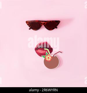 Lunettes de soleil en forme de chat, lèvres rouges et une noix de coco avec une paille sur fond rose. Concept surréaliste minimal pour la publicité exotique des vacances d'été Banque D'Images