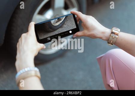 Accident de voiture. Gros plan sur la femme voyageur dans la ville avec un smartphone prenant des photos près d'une voiture avec pneu à plat. Banque D'Images