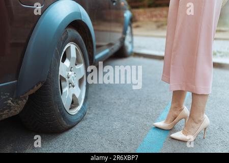 Accident de voiture. Gros plan sur la femme voyageur dans la ville près d'une voiture avec pneu à plat. Banque D'Images