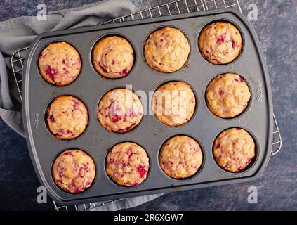 Muffins aux framboises fraîchement cuits dans un moule à muffins antiadhésif : muffins au petit déjeuner ou au dessert préparés avec des fruits directement vus du dessus dans un moule à muffins Banque D'Images