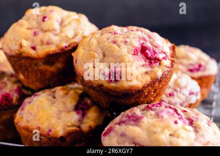 Muffins aux framboises fraîchement cuits empilés sur une grille de refroidissement gros plan : petits-déjeuners ou desserts à base de fruits vus de près Banque D'Images