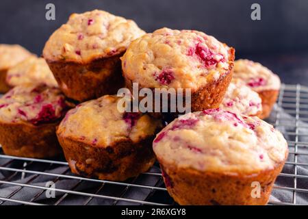 Muffins aux framboises fraîchement cuits empilés sur un panier de refroidissement en fil de fer vue latérale : muffins au petit déjeuner ou au dessert préparés avec des fruits vus dans le profil Banque D'Images