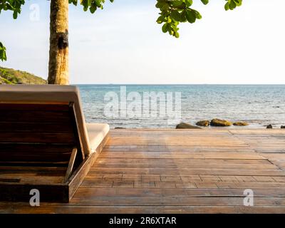 arrière de chaises longues en bois avec coussins de lit coussin décoration sur terrasse en bois sur la vue sur mer avec mer bleu océan, rochers et l'été coucher de soleil ciel dos Banque D'Images