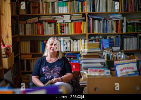 PRODUCTION - 25 mai 2023, Saxe-Anhalt, Mühlbeck: Myriam Gödicke est assis dans sa librairie d'antiquaires avec un livre dans sa main. L'Antiquariat Gödicke Alte Schule compte plus de 200 000 livres triés dans 35 domaines. Les fans de littérature, les addicts de livre et les bookworms sont attirés par le premier village de livre d'Allemagne - mais les libraires d'antiquaires n'ont pas de successeurs en vue 26 ans après sa fondation. Photo: Klaus-Dietmar Gabbert/dpa Banque D'Images