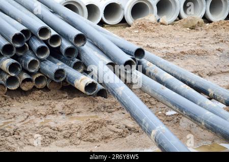 Grands tuyaux de plomberie d'égout en plastique noir pour la construction de tuyaux d'eau ou d'égouts sur un chantier de construction pendant la réparation. Arrière-plan, texture. Banque D'Images