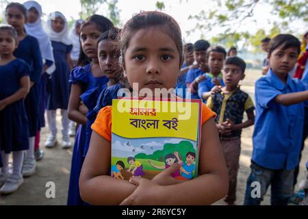 Un élève de l'école primaire tient de nouveaux manuels après les avoir reçus pour les nouvelles classes à Sirajdikhan à Munshiganj. Bangladesh. Le gouvernement distrib Banque D'Images