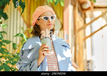 Femme élégante satisfaite avec une tasse de café à l'extérieur par beau temps Banque D'Images