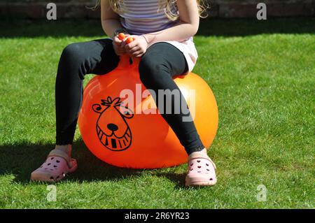 Une jeune fille assise sur sa trémie spatiale dans un jardin un matin d'été Banque D'Images