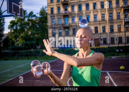 Bald women Jongling avec Crystal ball dans le parc Banque D'Images