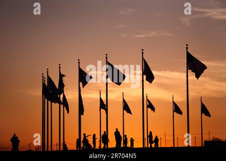 Les drapeaux et les visiteurs du Washington Monument sont détourés au coucher du soleil sur le Mall à Washington DC au printemps. Banque D'Images