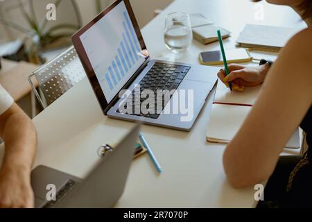 Gros plan de couple indépendants assis à table dans le salon avec des ordinateurs portables et travaillant à domicile Banque D'Images