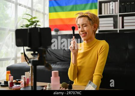 Charmant jeune gay homme blogger enregistrement maquillage tutorial, streaming en direct à la maison. LGBTQ Lifestyle, influenceur, blogueur Banque D'Images