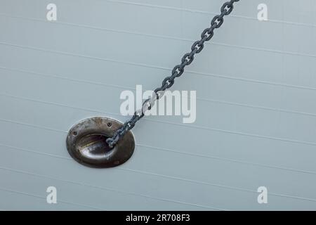 Une corde d'amarrage sortant du trou sur le côté d'un vieux navire en métal. Banque D'Images