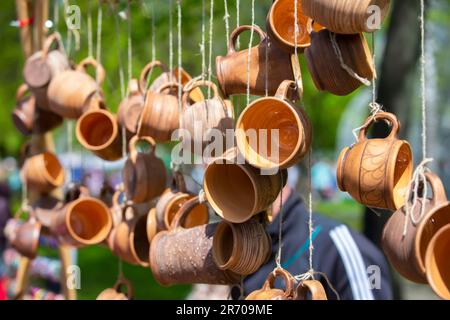 Les tasses en argile sont accrochées sur des cordes et vendues à la foire. Banque D'Images