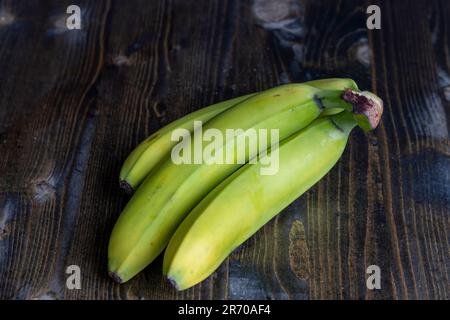 Bananes vertes non mûres sur la table, un bouquet de bananes vertes non mûres sur un tableau noir Banque D'Images