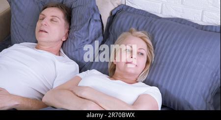 Ronflement homme. Couple au lit, homme ronflant et femme ne peut pas dormir. Couple d'âge moyen au lit à la maison. Banque D'Images