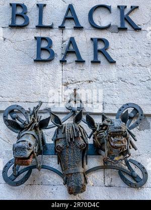 Oviedo, Asturies, Espagne: Un mur texturé avec les mots Black Bar en relief. Une sculpture en métal de têtes de cheval est accrochée à un clou Banque D'Images