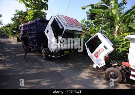 10 juin 2023, Kulonprogo, Yogyakarta, Indonésie: Un mini camion passe devant un vrai camion dans un village résident de Kulonprogo, Yogyakarta, le 12 juin 2023. Le chariot utilise un moteur de moto modifié. Le camion à jouets a une conception qui ressemble à un camion en général, mais a des dimensions beaucoup plus petites avec des fonctions avant, arrière et de levage derrière le lit. Un jeune homme nommé Imam, le propriétaire de Rimbono garage, a déclaré que le but de fabriquer le mini-camion était initialement seulement de répondre aux demandes des fans sur les médias sociaux. parce qu'avant de fabriquer des voitures jouets, le corps du camion était purement fait à la main f Banque D'Images