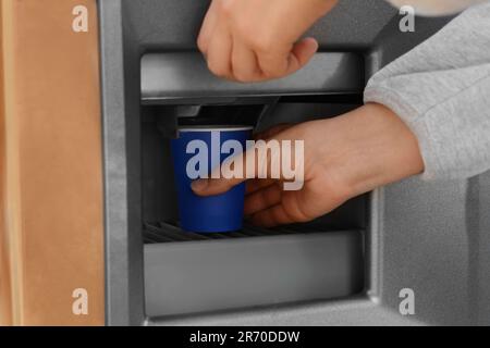 Femme prenant une tasse en papier avec du café du distributeur automatique, gros plan Banque D'Images