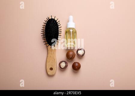 Délicieux noix de macadamia bio, huile cosmétique et pinceau sur fond beige, plat Banque D'Images