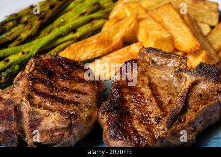 Côtelettes d'agneau grillées avec pommes de terre frites et asperges. Gros plan. Banque D'Images