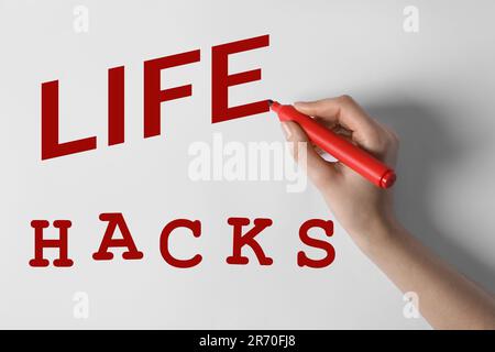 Femme écrivant des mots Life Hacks sur le tableau blanc, gros plan Banque D'Images