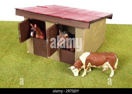 Une ferme en bois avec des chevaux et un jouet de vache Banque D'Images