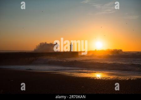 Immense vague au phare de Felgueiras à Porto au coucher du soleil, Portugal. Banque D'Images