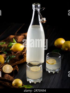 Un cliché vertical d'une bouteille de verre remplie de limonade avec des citrons frais sur une table Banque D'Images