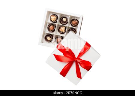 Bonbons au chocolat dans une boîte avec un noeud de couleur. Boîte cadeau avec chocolats isolés sur le toit blanc vue. Banque D'Images