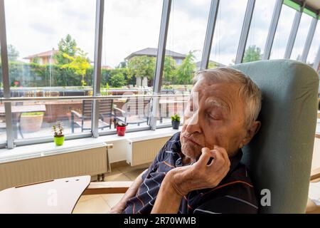 pensionné de la vieillesse assis à la table dans la maison de repos Banque D'Images