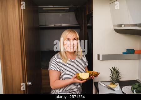 une femme cuisant de la nourriture dans la cuisine à l'intérieur d'un autocaravane, à l'intérieur d'un autocaravane. Banque D'Images