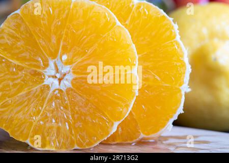 Couper l'orange juteuse pendant la cuisson sur la table, l'orange couché sur la table avec d'autres fruits et de la nourriture Banque D'Images