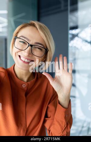 Prise de vue verticale, jeune femme d'affaires très belle qui parle lors d'un appel vidéo, agitant la caméra d'un smartphone à l'aide d'une application de communication à distance. Banque D'Images