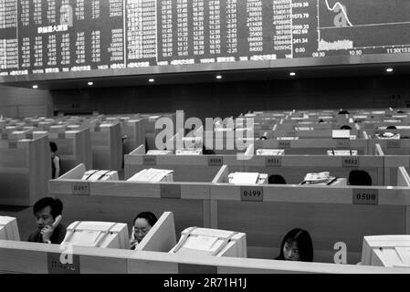 Shanghai Chine 2000. « Gilets rouges » sur le plancher de négociation du bâtiment de la Bourse de Shanghai à Pudong, qui a ouvert fin 1997. La plus importante de Chine continentale, la bourse n'a été créée qu'à Shanghai en 1990, mais compte maintenant plus de 600 sociétés cotées et le marché est numéro deux dans la région Asie-Pacifique. La politique du gouvernement consiste à encourager les individus à participer au marché boursier, car de nombreuses sociétés cotées sont détenues par l’État, ou appartenant à l’État, et ont cruellement besoin de capitaux. 2000s HOMER SYKES Banque D'Images