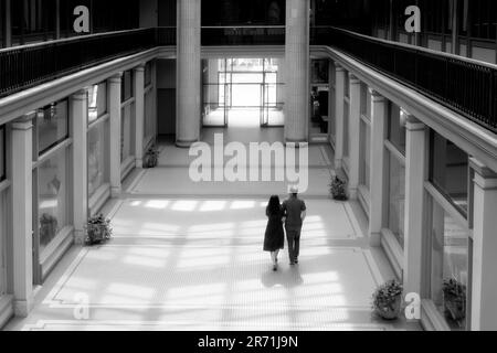 Couple marche à travers la lumière du soleil dans ce bâtiment d'arcade du milieu du siècle Banque D'Images