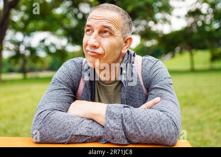 Beau homme d'âge moyen, aux yeux bruns, aux cheveux gris, gros plan sur un parc d'été vert flou Banque D'Images